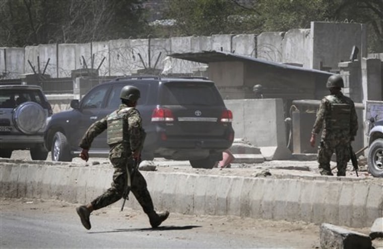 FILE - In this April 18, 2011 file photo, an Afghan soldier runs near the gate of Defense Ministry in Kabul, Afghanistan, where a gunman in an army uniform gunned down two Afghan soldiers before being killed. The gunman also fatally wounded an Afghan army officer who died later at a hospital. The attack, brazen and cleverly orchestrated by insurgents, is indicative of the high-profile yet small-scale attacks that are trademarks of the Taliban's spring campaign. (AP Photo/Musadeq Sadeq, File)